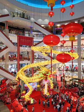 Kuala Lumpur, Malezya - 12 Şubat 2024: Malezya 'nın başkenti Kuala Lumpur' da bulunan lüks bir alışveriş merkezi olan Pavilion alışveriş merkezinde ejderha ve kırmızı fenerli Çin Yeni Yıl süsleri bulunan mağazaların iç görünümü.