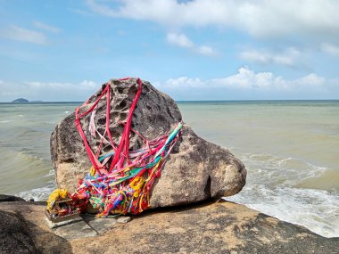 Thai Buddhist temple Wat Khao Saen which includes a boulder on the beach with offerings locally named Hua Nai Raeng located in Songkhla, Thailand. clipart