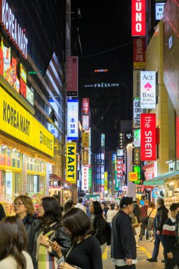 Seul, Güney Kore - 26 Ekim 2024: Canlı ve hareketli alışveriş bölgesi Myeong-Dong 'un Seul, Güney Kore' de bulunan ışıklı tabelalarla dolu olduğu sokak manzarası. 