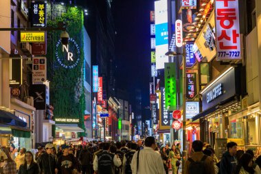 Seul, Güney Kore - 26 Ekim 2024: Canlı ve hareketli alışveriş bölgesi Myeong-Dong 'un Seul, Güney Kore' de bulunan ışıklı tabelalarla dolu olduğu sokak manzarası. 