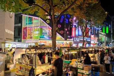 Seul, Güney Kore - 26 Ekim 2024: Canlı ve hareketli alışveriş bölgesi Myeong-Dong 'un Seul, Güney Kore' de bulunan ışıklı tabelalarla dolu olduğu sokak manzarası. 