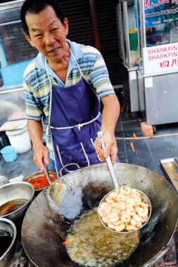 Georgetown, Penang, Malezya - 22 Temmuz 2014: Çinli Malezyalı adam yol kenarındaki bir gıda tezgahında Malezya usulü kızarmış erişte pişiriyor.