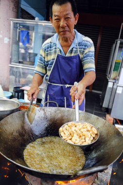 Georgetown, Penang, Malezya - 22 Temmuz 2014: Çinli Malezyalı adam yol kenarındaki bir gıda tezgahında Malezya usulü kızarmış erişte pişiriyor.