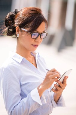 Malezyalı gülümseyen, göz kapağı takan ve akıllı telefon üzerinde çalışan yetişkin bir kadının portresi. İş kavramı kendinden emin ve başarılı iş kadını.