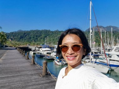 Genç Asyalı kadın Langkawi Adası, Kedah Malezya 'daki Telaga limanında selfie çekiyor..