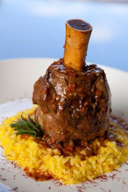 Safranlı risotto üzerine servis edilen bir parça ossobuco dana inciği..