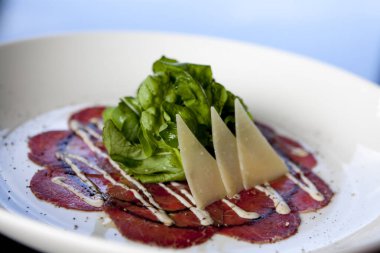 Parmesan peynirli çiğ sığır eti carpaccio roka salatası. Carpaccio ince dilimlenmiş ya da dövülmüş ettir ve Venedik, İtalya 'da yaratılmıştır.. 