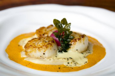 Kırmızı biber soslu ve beyaz tabakta Hollandaise soslu kızarmış deniz tarağı.. 