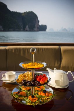 Tayland, Phuket yakınlarındaki Phang Nga Körfezi 'nde lüks bir yatta üç katmanlı bir yemek sunucusuyla ikindi çayı..