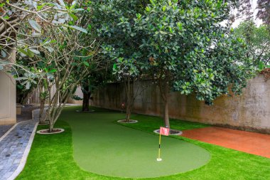 Phnom Penh, Kamboçya - 18 Şubat 2025: Kamboçya 'da Phnom Penh, Kamboçya' da lüks bir villanın arka bahçesine yapay çim çimenliği ve spor amaçlı bir golf sahası.