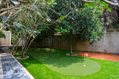 Phnom Penh, Kamboçya - 18 Şubat 2025: Kamboçya 'da Phnom Penh, Kamboçya' da lüks bir villanın arka bahçesine yapay çim çimenliği ve spor amaçlı bir golf sahası.