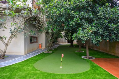 Phnom Penh, Kamboçya - 18 Şubat 2025: Kamboçya 'da Phnom Penh, Kamboçya' da lüks bir villanın arka bahçesine yapay çim çimenliği ve spor amaçlı bir golf sahası.