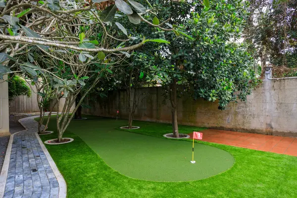 Phnom Penh, Kamboçya - 18 Şubat 2025: Kamboçya 'da Phnom Penh, Kamboçya' da lüks bir villanın arka bahçesine yapay çim çimenliği ve spor amaçlı bir golf sahası.