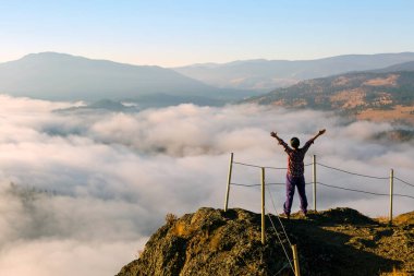 Dev Başlı Dağ 'ın zirvesinde kolları açık bir turist aşağıdaki vadi ve gölü kaplayan sis manzaralı Summerland, British Columbia, Kanada' daki Okanagan Vadisi 'nde.