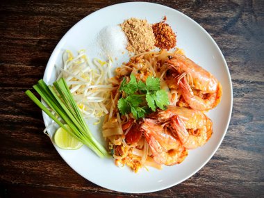 Limon, fasulye filizi ve taze otlarla süslenmiş, Tayland mutfağının lezzetlerini gösteren otantik Tayland eriştesinin tadını çıkarın..