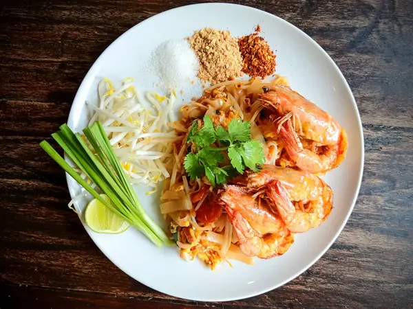 Limon, fasulye filizi ve taze otlarla süslenmiş, Tayland mutfağının lezzetlerini gösteren otantik Tayland eriştesinin tadını çıkarın..