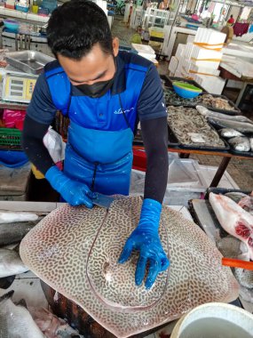 Penang, Malezya - 10 Ocak 2025 Malezya 'da bir balıkçı ustalıkla Penang, Malezya' daki bir balık pazarında vatoz temizliyor.. 