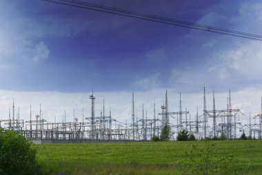 Koyu mavi gökyüzünün arka planında yeşil çimenli bir arazide bulunan elektrik direkleri. Yüksek kalite fotoğraf