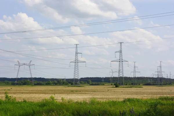 stock image The power poles are located among a green field, against a blue sky with white clouds. High quality photo