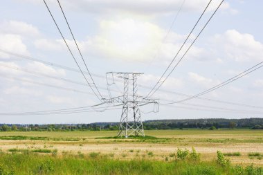 Tarlada elektrik kabloları olan büyük bir direk, bulutlu gökyüzüne karşı. Yüksek kalite fotoğraf