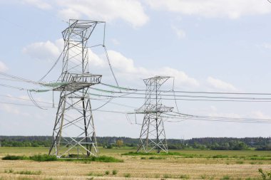 Yüksek ve alçak elektrik direkleri beyaz bulutlarla gökyüzüne karşı. Yüksek kalite fotoğraf