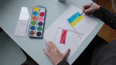 Çocuk Polonya ve Ukrayna 'nın bayraklarını boyuyor. Çizimini bitirdikten sonra, çalışmalarını eleştirir. Yüksek kalite 4k görüntü