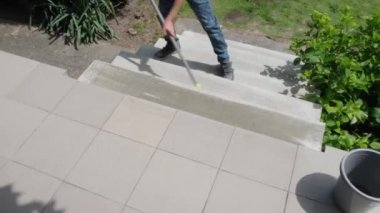 Güneşli bir yaz gününde bir çocuk bir kır evinin merdivenlerini paspasla yıkıyor. Yüksek kalite 4k görüntü