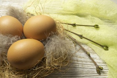 Three orange eggs lie in a nest on a table, on wooden boards. Easter card for the holiday. High quality photo