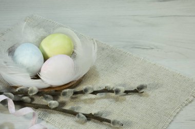 Three colorful eggs with willow branches lie on the table. Festive composition for Easter. High quality photo