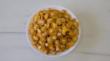 Cantharellus cibarius mantarları bir tabakta, mutfaktaki masanın üzerinde. Yüksek kalite 4k görüntü