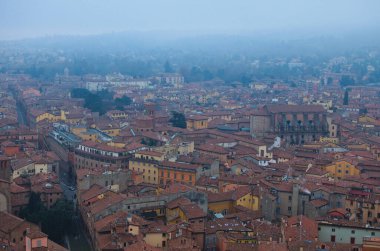 Scenic bird-eye view from the top of the tower on Bologna old town center. Vintage buildings with red tile roofs. Famous touristic place and travel destination in Europe. UNESCO World Heritage Site.