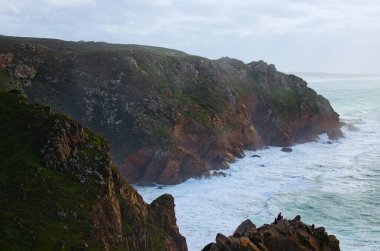 Stormy ocean with waves braking on the cliffs. Overcast weather, stormy wind. Scenic morning foggy landscape. Atlantic ocean, Cape Roca (Cabo da Roca), Portugal. Travel and tourism concept.