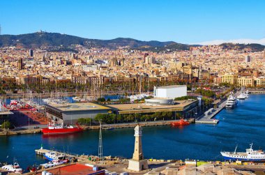 Picturesque aerial landscape view of Port Vell with moored yachts and ships in Barcelona. Downtown of Barcelona in the background. Travel and tourism concept. Cityscape at sunny day.