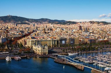 Picturesque aerial landscape of historic part of Barcelona during sunny day. Embankment, harbor with moored yachts on the foreground. View from the cable car. Travel and tourism concept.
