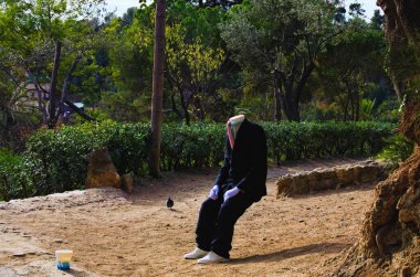 Barcelona, Spain-January 03,2016:Close-up view of a street artist in costume pretends to be a statue sitting in the air without any chair. Street performance of a man without a head. Park Guell.