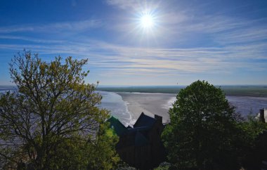 Su ve kara arasındaki savaşın resimli manzarası. Yüksek gelgit suyu Mont Saint-Michel Manastırı 'nın duvarlarına gidiyor. Seyahat ve turizm konsepti. UNESCO Dünya Mirası Alanı. Normandiya, Fransa.