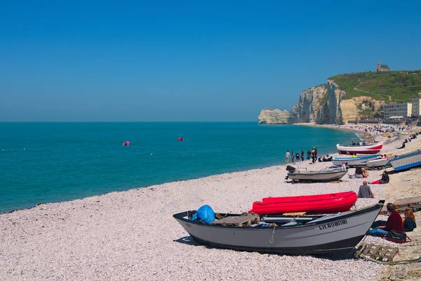 stock image Etretat, France-May 05, 2018:Beautiful nature landscape photo of resting people in pebble beach at Etretat. Colorful wooden fishing boats on the shore. White chalk cliffs in the background.