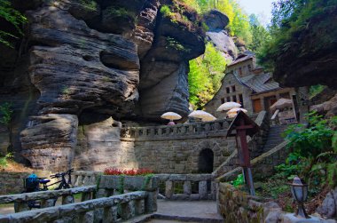 Ormandaki kayaların arasındaki klasik taş binanın manzarası. Bohemian İsviçre ulusal parkı. Ünlü turistik yer ve seyahat merkezi..