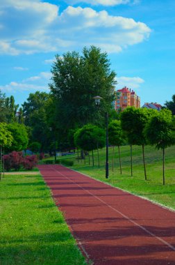 Şehir parkında boş koşu pisti. Lastik kaplama. Ukrayna, Kyiv 'deki Natalka parkında kırmızı koşu bandı. Sağlıklı spor anlayışı.