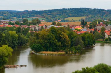 Ortaçağ binaları ve göl ile sık ormanlarla kaplı kırmızı kiremit çatıların resimli hava manzarası. Çek Cumhuriyeti 'nin tipik küçük kasabası. Seyahat ve turizm kavramı.