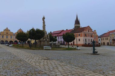 Veba Sütunu ve arka planda renkli rönesans binaları olan antik pazar meydanının resimli manzarası. Telc 'in ikonik simgesi. UNESCO Dünya Mirası Alanı.