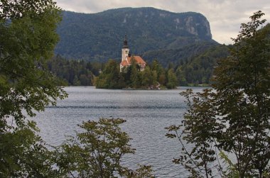 Bled Gölü manzaralı bir ada ve arka planda dağlar. Slovenya 'nın en ünlü gölü. Ağaç sınırı terk eder. Doğal çerçeve. Manzara ve doğa kavramı.