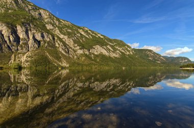 Slovenya 'nın Triglav Ulusal Parkı' ndaki Bohinj Gölü 'nün turkuaz suyuna yansıyan manzaralı dağ manzarası hayret verici bir manzara. Manzara ve doğa kavramı.