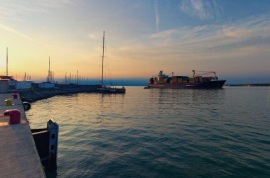 Koper limanında büyük bir kargo gemisi manevra yapıyor. Slovenya 'nın Koper limanının geniş açılı manzarası. İhracat işi lojistiği. Uluslararası gemi ulaşımı.