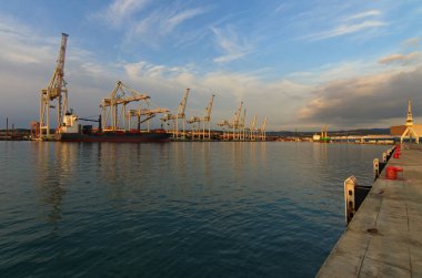 Slovenya 'nın Koper limanının geniş açılı manzarası. Konteynır kargo gemisine endüstriyel vinçlerle yükleniyor. İhracat işi lojistiği. Uluslararası gemi ulaşımı.
