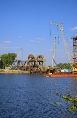 Nehir üzerinde yeni bir yaya köprüsü inşa etmek için çelik yapıların monte edilme sürecine bakın. Köprü inşa ediliyor. Ukrayna, Kyiv 'deki Obolon mahallesi.