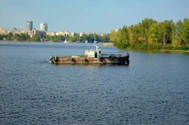 Yakın çekim yelkenli römorkör gemisi. Dnipro nehrindeki eski paslı gemi. Arka planda Obolon mahallesi, Kyiv, Ukrayna.