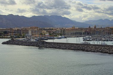 Palermo 'daki limanın yakınındaki, demirlemiş yatları ve tekneleriyle muhteşem bir manzara. Arka plandaki antik binalar. Dağ sırasının üzerinde canlı bir gökyüzü. Seyahat ve turizm kavramı.
