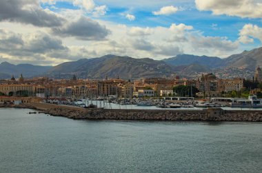 Palermo 'daki limanın yakınındaki deniz manzarası. Çapalı yatları ve tekneleri var. Arka plandaki antik binalar. Dağ sırasının üzerinde canlı bir gökyüzü. Seyahat ve turizm kavramı.