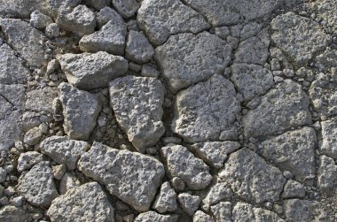 Derin oyuklarla detaylı bir bakış açısı. Toprak yol parçasının görüntüsü. Kuru topraklar taşlarla dolu. Soyut doğal dokulu arka plan. Yerdeki taşlar ve çakıl taşları.